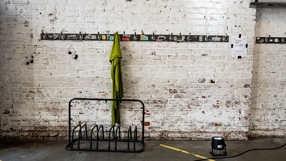 Fahrradständer vor einer weißen gemauerten Wand mit Jackenhacken