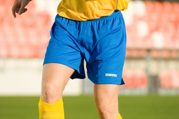 Person in blaugelber Sportbekleidung, Ausschnitt nur Sporthose mit Beinen